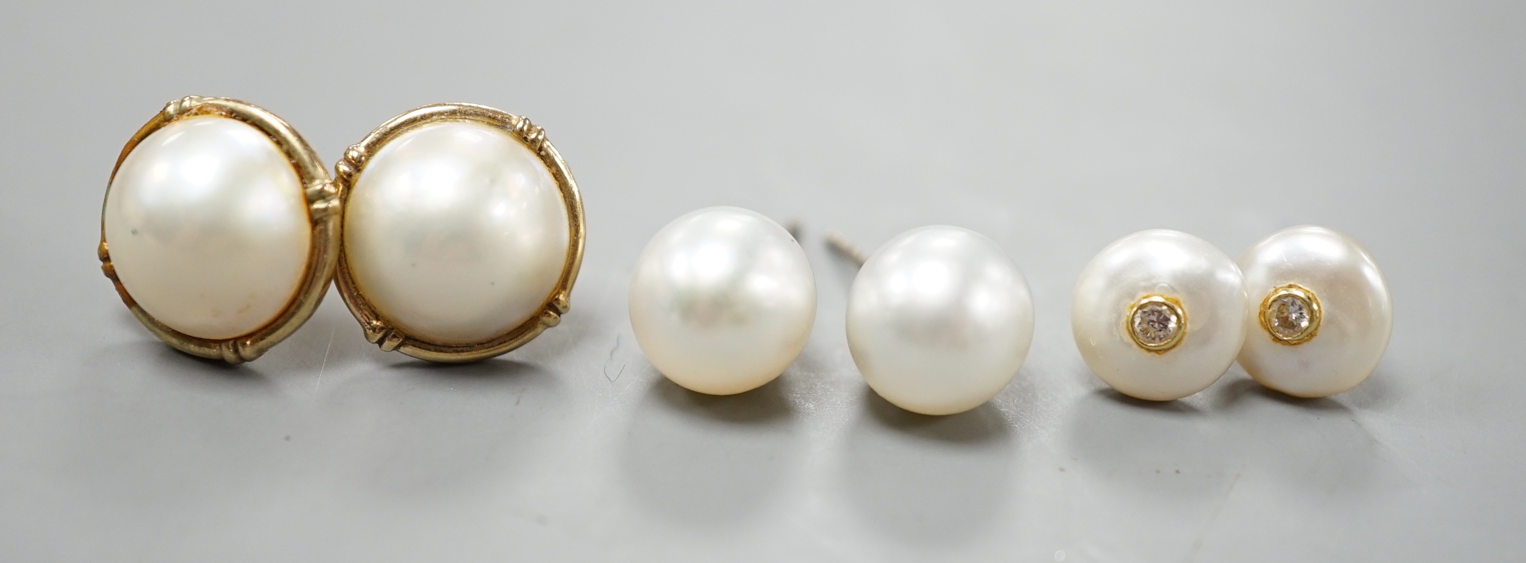 A pair of 18ct and cultured pear ear studs, a pair 9ct gold and mabe pearl ear studs and a pair of 18k, cultured pearl and diamond set ear studs (all lacking butterflies).